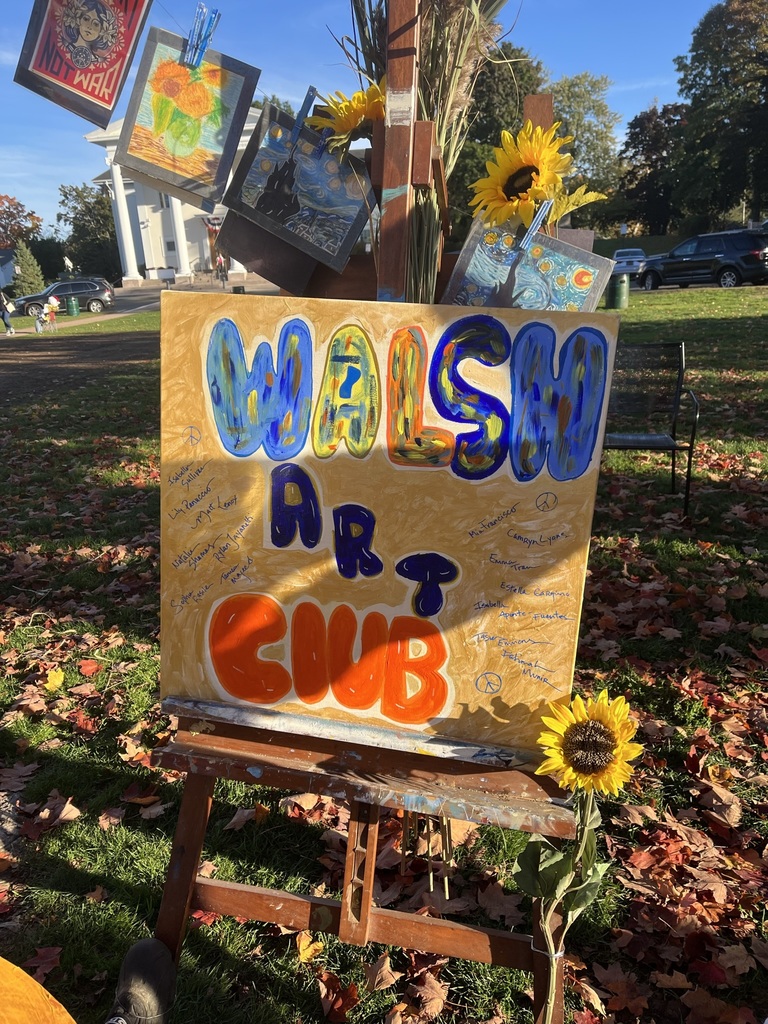 hand made walsh art club sign amongst sunflowers outside
